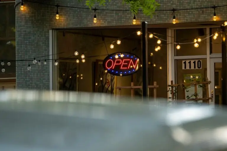 An open sign glows in a storefront window at night.
